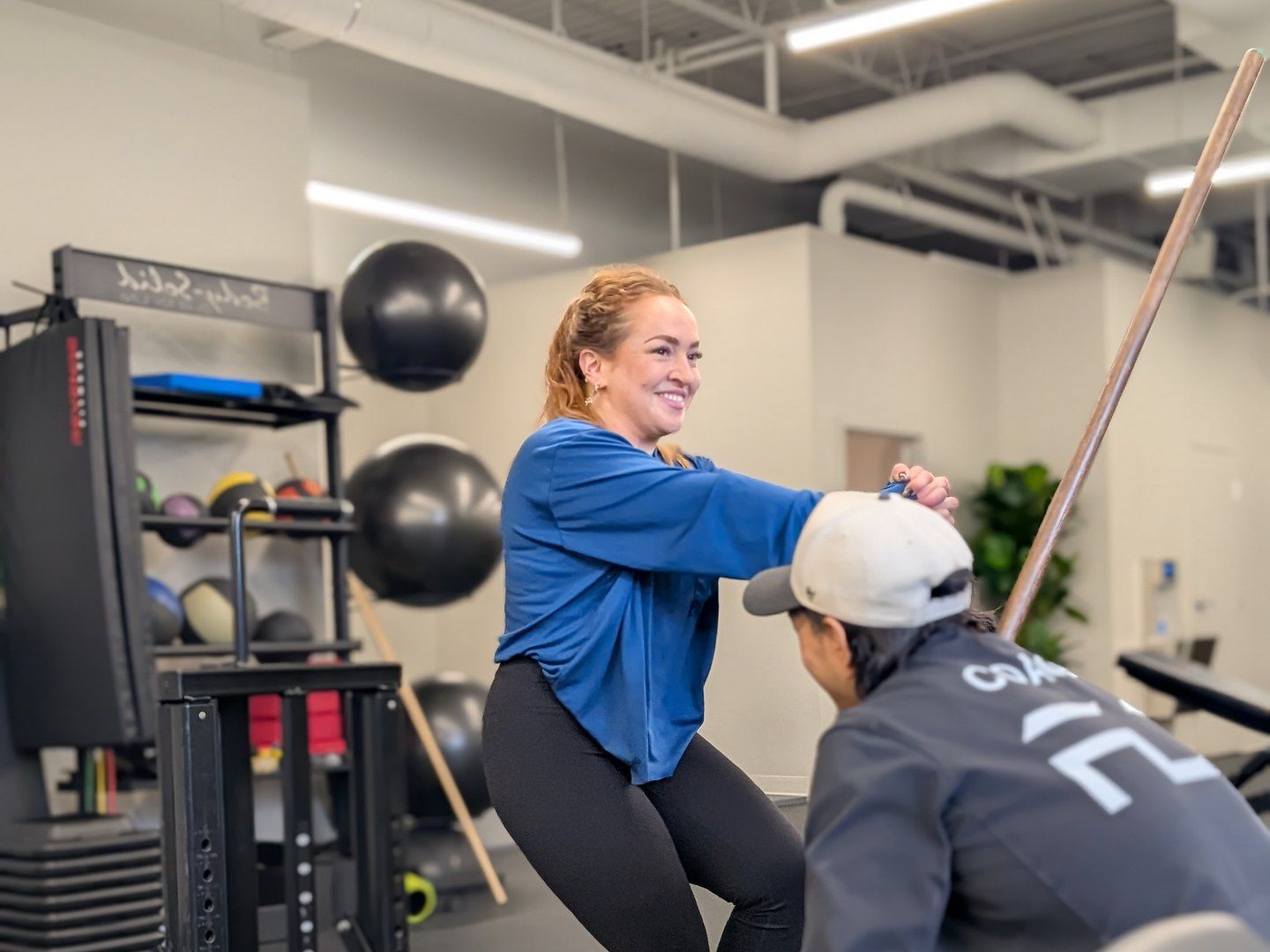 Une cliente fait un squat pendant qu’un kinésiologue de FD Fitness observe son mouvement
